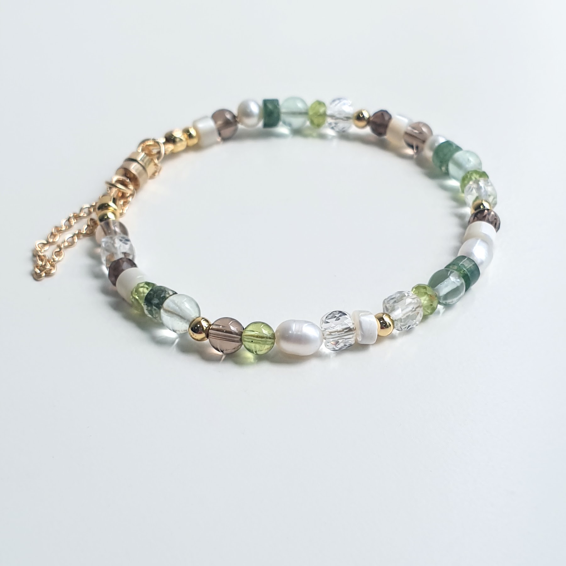 A handcrafted chain bracelet featuring Pearl, Peridot, Smoky Quartz, Moss Agate, Fluorite, Mother of Pearl and Clear Quartz by Red Lotus.