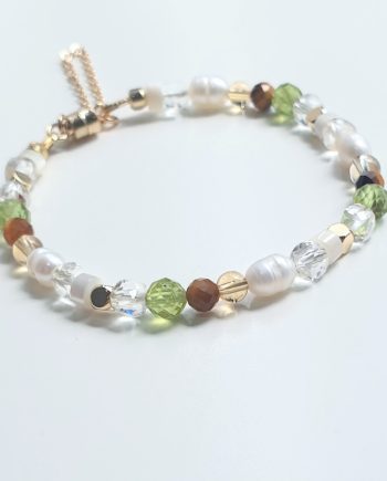 A handcrafted chain bracelet featuring Pearl, Peridot, Tiger’s Eye, Clear Quartz, Mother of Pearl and Citrine by Red Lotus.